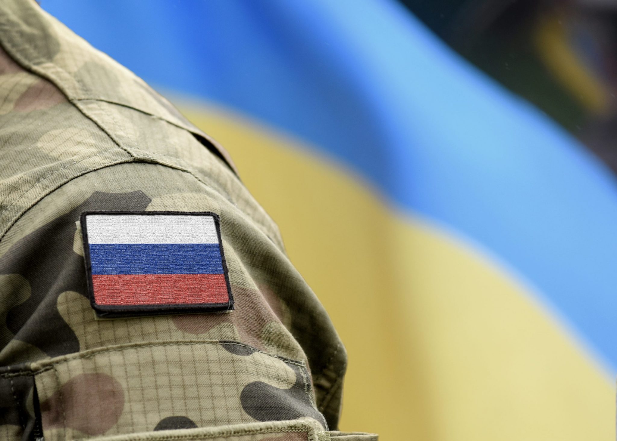 Flag of Russia on military uniform and flag of the Ukraine at background. Russia VS Ukraine.