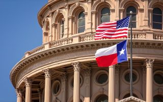 American and Texas state flags flying on the dome of the Texas State Capitol building in Austin