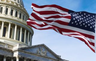 American flag waving with the US Capitol Hill in the background