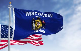 The Wisconsin state flag waving along with the national flag of the United States of America. Wisconsin is a state in the upper Midwestern United States