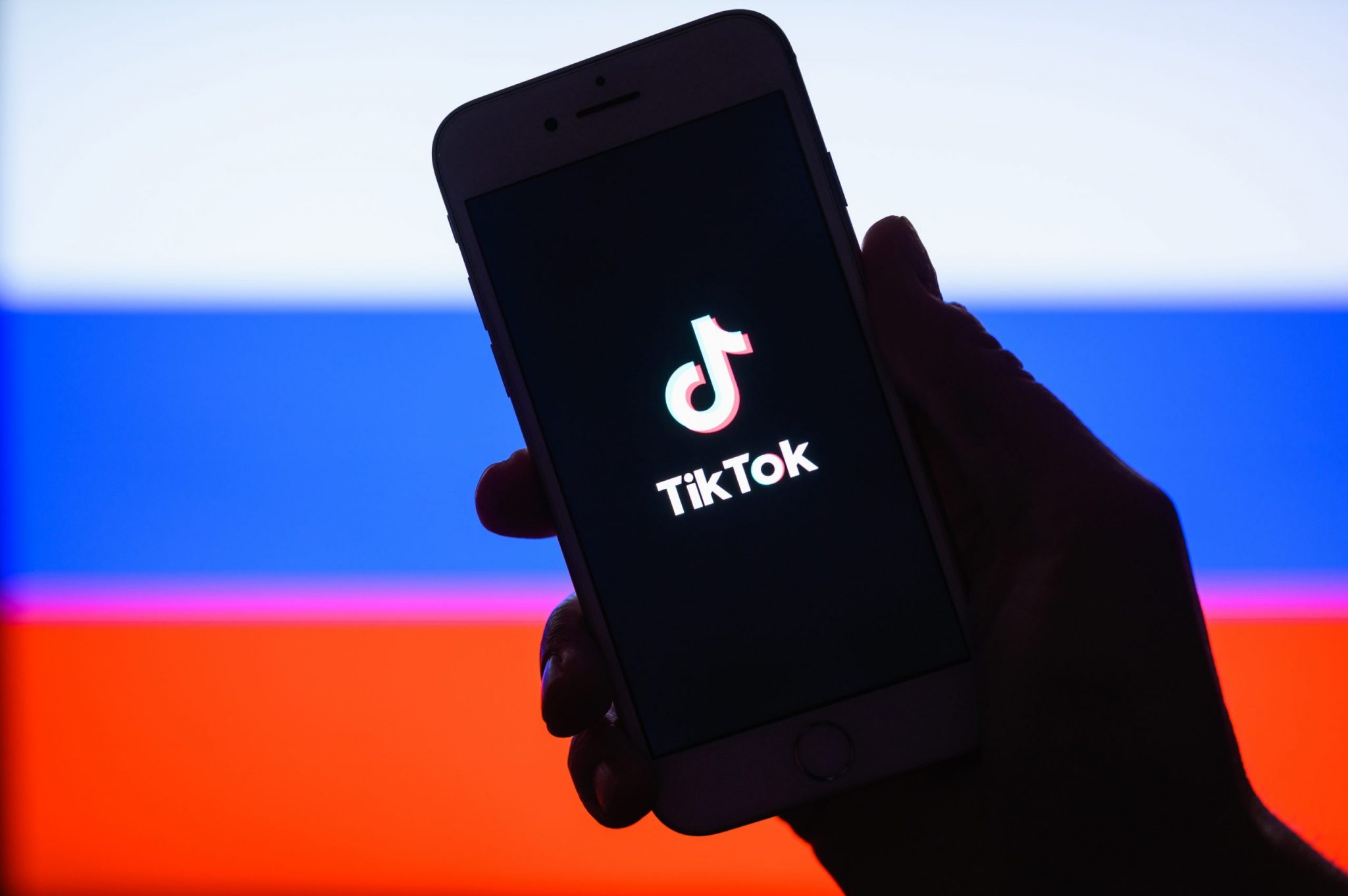 Tik Tok application on a smartphone against the background of the Russian flag.