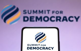 In this photo illustration the Summit for Democracy logo seen displayed on a smartphone and on the background