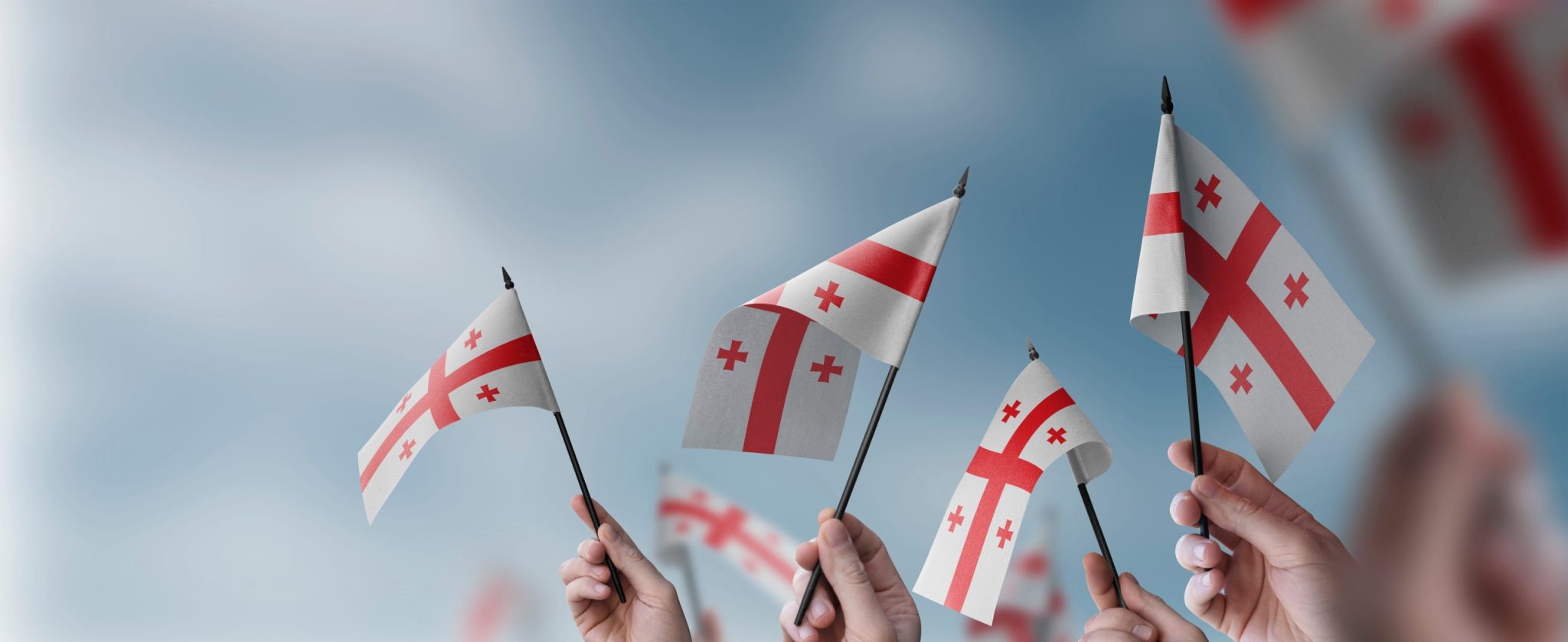A group of people holding small flags of the Georgia in their hands.