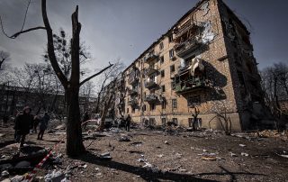 damaged building in Ukraine with soldiers walking on the side